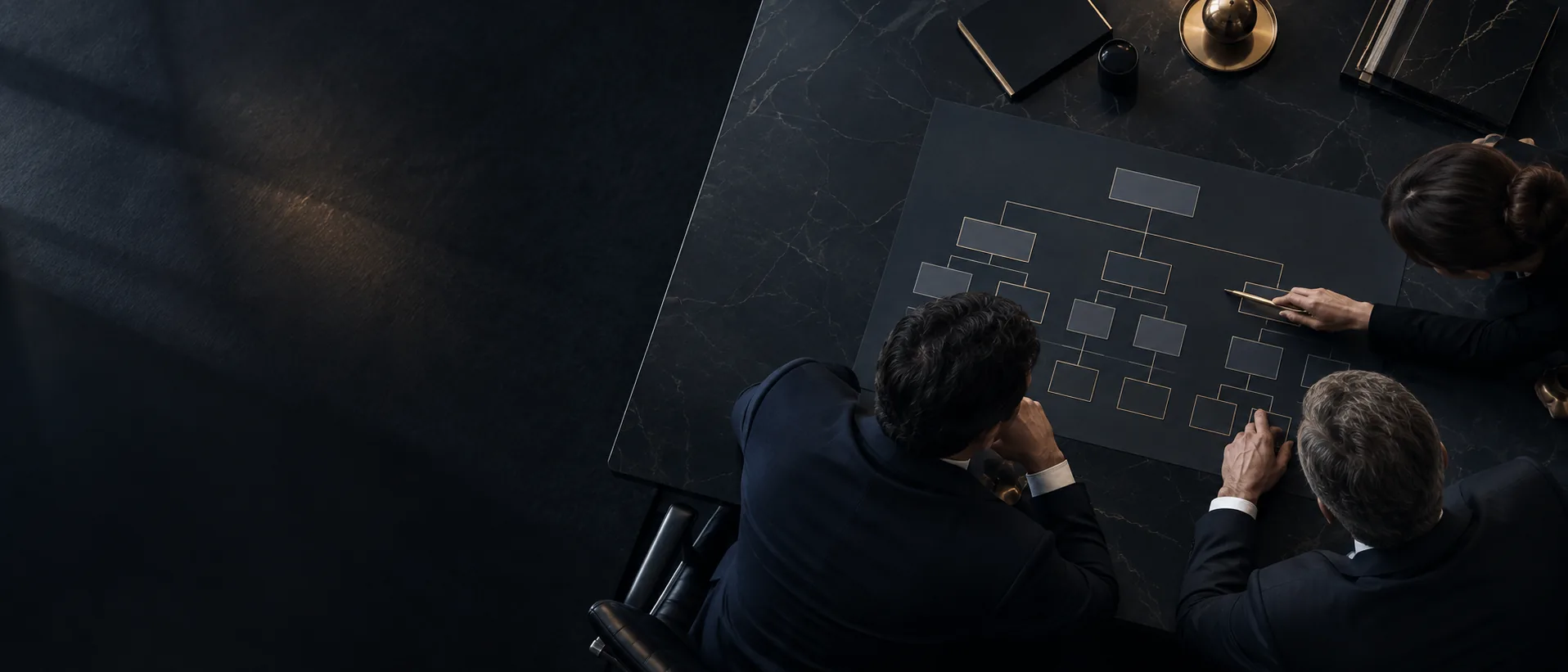 Three advisers reviewing an ownership structure chart on a meeting table